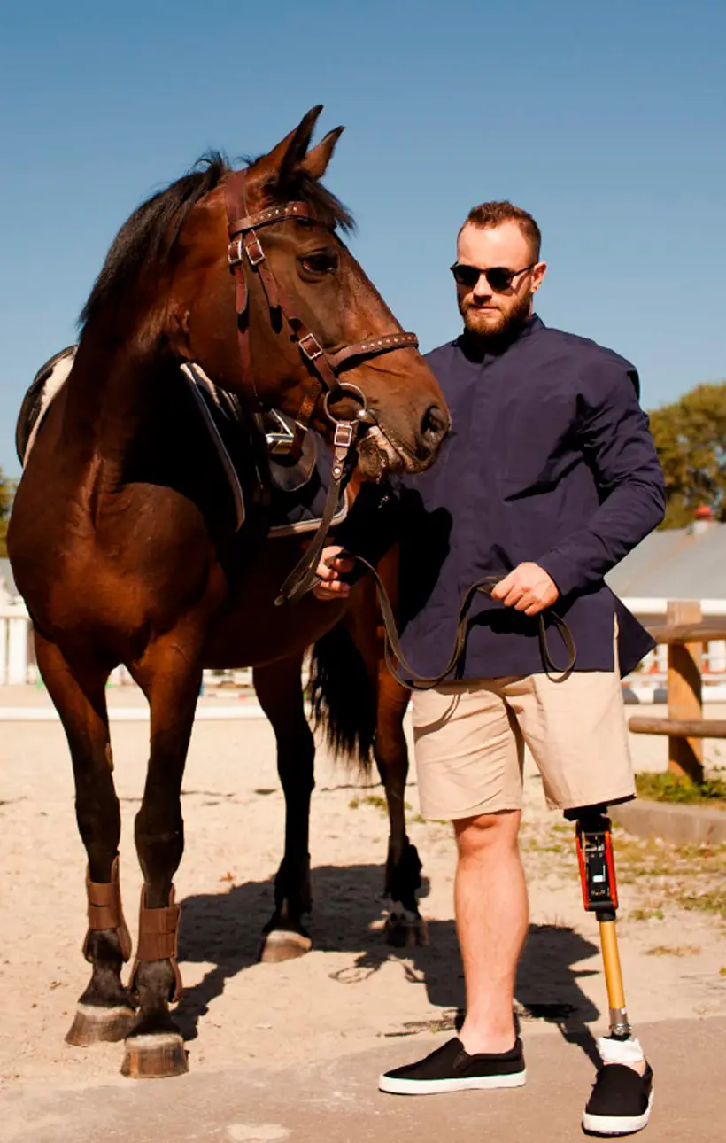 Man with sunglasses next to a horse, with a leg prosthesis