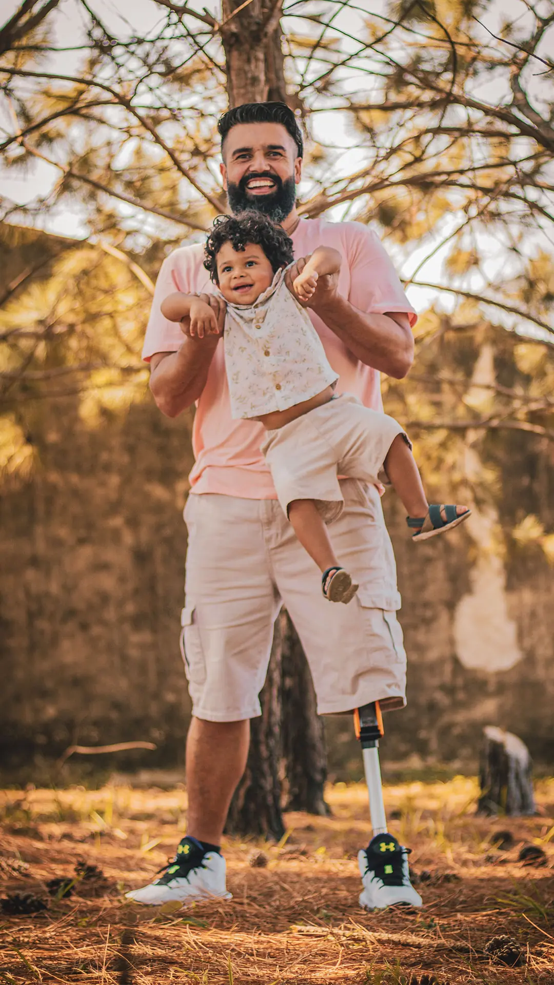Father with a leg prosthesis carrying his son in a wooded area