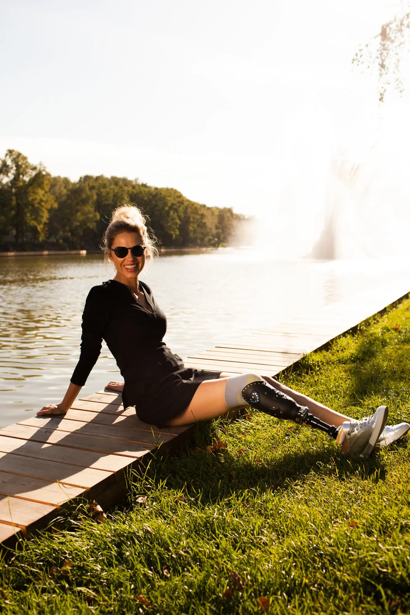 Woman sitting on a deck by the lake, with a leg prosthesis